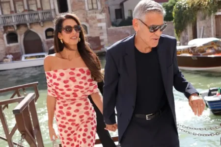 Amal wearing raspberry print dress with George Clooney in Venice