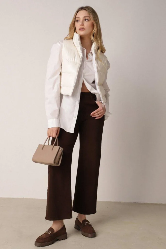 Woman wearing brown jeans with leather loafers, a white shirt, and beige blazer for a smart casual look