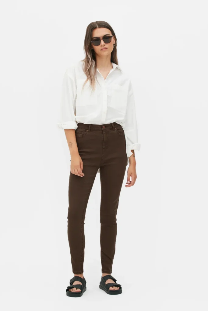 Woman wearing brown jeans with a light blue button-down shirt for a relaxed smart casual outfit