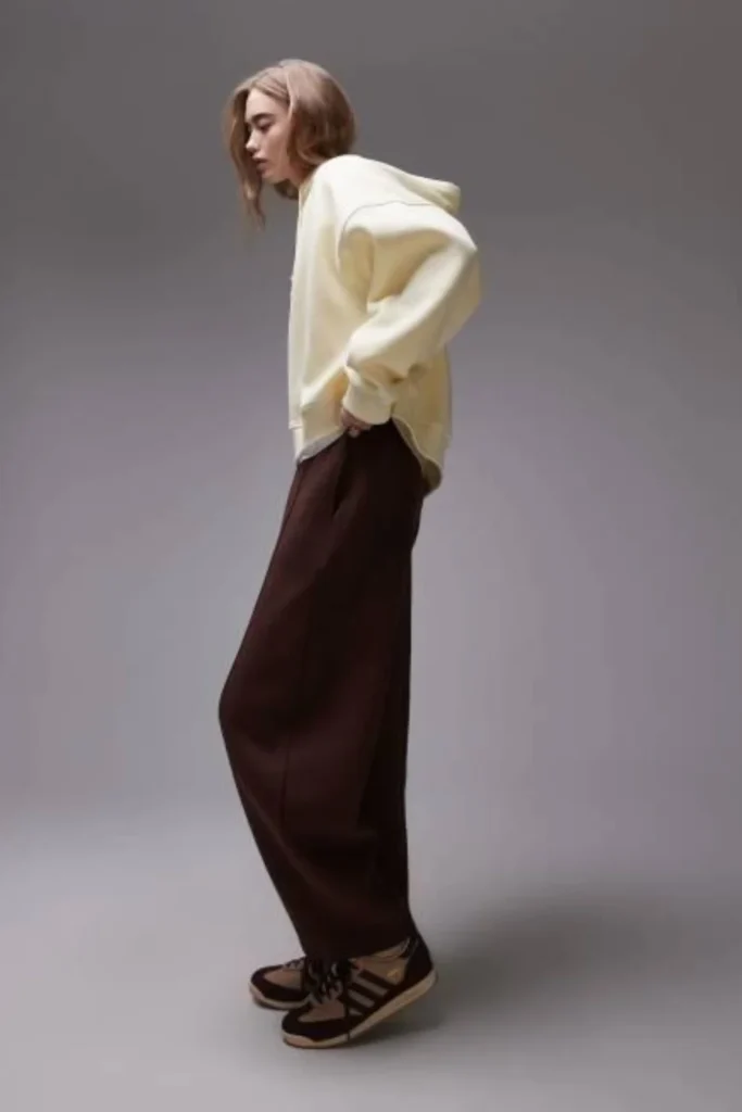 Woman wearing relaxed brown jeans with an oversized cream hoodie and chunky sneakers