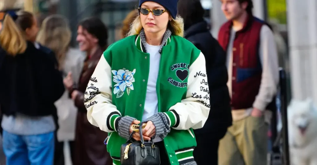 Gigi Hadid wearing a green and white varsity jacket with casual streetwear pieces